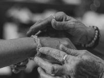 A detailed monochrome shot showing a bracelet being gently fastened on a wrist.